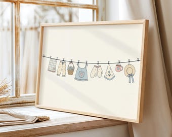 May include: A framed horizontal print featuring a line drawing of laundry hanging on a clothesline. The items include a checkered cloth, patterned pants, a basket of flowers, a blue apron, mittens, a floral handkerchief, a mug, and a straw hat.