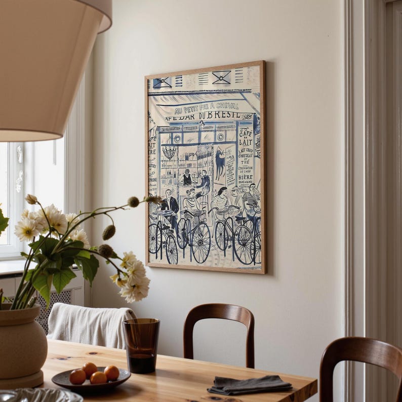 May include: A rectangular framed wall art print featuring a blue and white line drawing of a French cafe scene titled AU PETIT PAS A CHEVAL CAFE BAR DU BRESTE, depicting people seated at tables and bicycles parked in front of the storefront.