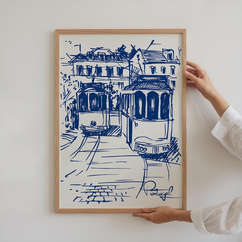 May include: A blue and white sketch of two vintage trams in Lisbon, Portugal. The trams are drawn in a simple, stylized way, with the buildings in the background also sketched in blue.