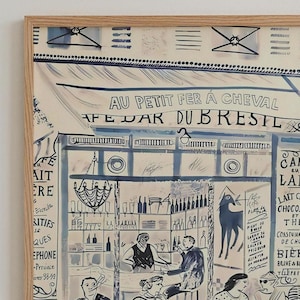 May include: A framed art print featuring a stylized illustration of a cafe interior with the text AU PETIT FER A CHEVAL and CAFE BAR DU BRESIL. The artwork uses blue and black ink on a cream background, depicting figures, bottles, and a horse.