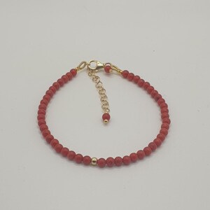 Può includere: Un braccialetto di perline di corallo rosso con chiusura e catena di estensione dorata.