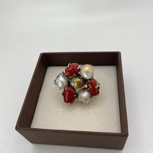 May include: A silver ring with a cluster of red coral and white pearls. The ring is in a brown box.