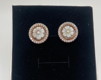May include: A pair of gold tone earrings with a white flower design set in a circle of clear rhinestones.