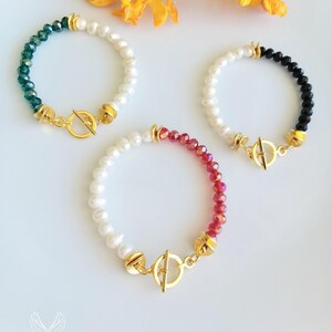 Puede incluir: Tres pulseras de tono dorado con cuentas de perlas y cristales. Las pulseras tienen un cierre de palanca. Las pulseras son verdes, negras y rojas.