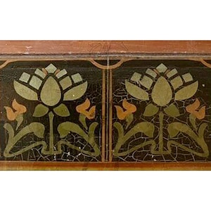 Op de afbeelding: Een close-up van een decoratieve tegelrand met een herhalend patroon van gestileerde groene en oranje bloemen op een zwarte achtergrond. De tegelrand heeft een bruin houten frame.