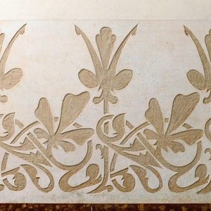 May include: A close-up of a white wall with a repeating pattern of carved floral designs. The design features stylized leaves and flowers in a light brown color.