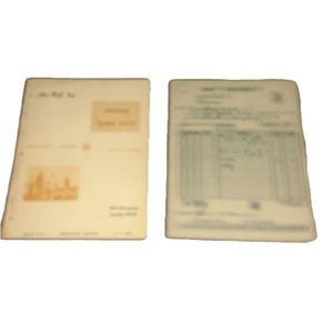 May include: Two rectangular off-white paper documents. The left document features a light orange rectangular block, a small orange illustration of a building, and printed text. The right document displays a grid-like table with rows and columns.
