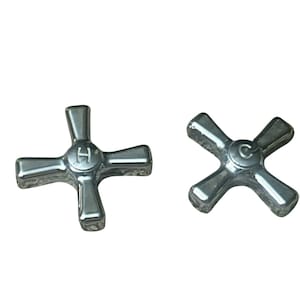 May include: Two chrome-finished metal tap handles with a four-point cross design. One handle features the letter H embossed in the centre, while the other handle features the letter C embossed in the centre. Both handles have a smooth, reflective surface.