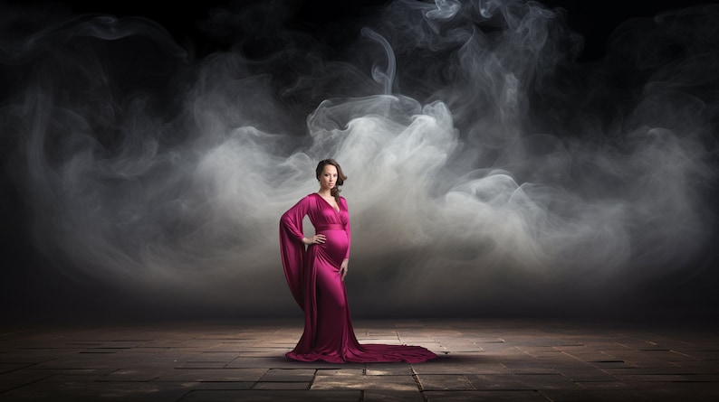 May include: A pregnant person in a long, flowing, magenta gown stands in a smoky, dark studio setting. The person is looking directly at the camera with a neutral expression.