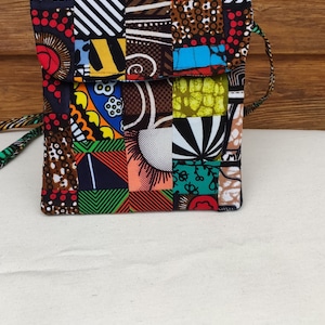 May include: A small patchwork fabric bag with a colorful geometric pattern. The bag has a flap closure and a strap.