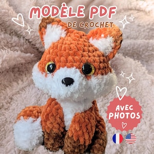 Peut inclure: Un renard en crochet fait à la main, avec des fils orange, blancs et marron. Le renard a de grands yeux brillants et un nez noir. L'image contient le texte "MODELE PDF DE CROCHET" et "AVEC PHOTOS".
