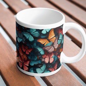 Puede incluir: Taza de cerámica blanca con un patrón de mariposas coloridas. Las mariposas son en tonos de azul, naranja, rojo y marrón.