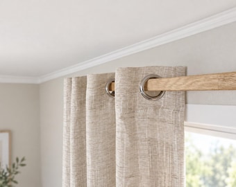 May include: A beige curtain with a subtle horizontal textured weave pattern hanging from a light-colored wooden rod. The curtain features evenly spaced silver-toned metal grommets that allow the fabric to slide along the square-shaped rod.