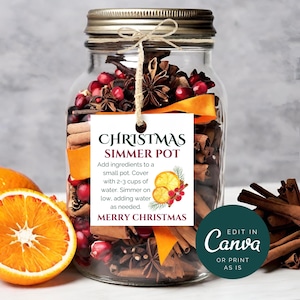 Könnte beinhalten: Ein Glas gefüllt mit Zutaten für einen Weihnachts-Schmortopf, darunter Zimtstangen, Sternanis, Orangenschalen, Preiselbeeren und Nelken. Ein weißes Etikett, das an dem Glas befestigt ist, lautet "Christmas Simmer Pot" und enthält Anweisungen zur Verwendung. Das Etikett lautet auch "Merry Christmas". Ein grüner Kreis mit weißem Text lautet "In Canva bearbeiten oder so drucken".