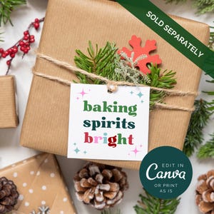 Puede incluir: Una etiqueta de regalo blanca con el texto "baking spirits bright" en letras de colores. La etiqueta est&aacute; decorada con estrellas verdes, azules y rosas. La etiqueta est&aacute; atada con una cuerda a una caja de regalo marr&oacute;n envuelta en papel marr&oacute;n y decorada con ramas de pino y un copo de nieve rojo.