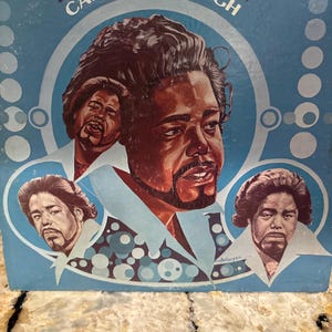 May include: A square vinyl record cover featuring the album title Can't Get Enough and the artist name Barry White in dark purple text. The blue background displays three painted portraits of Barry White and a pattern of light blue circles.