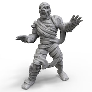 May include: A gray painted miniature figurine of a mummy, standing with arms outstretched, with a detailed, textured surface.