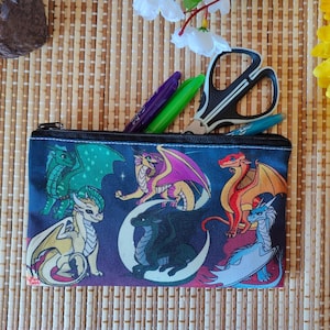 May include: A zippered pencil case with a dragon illustration. The case is dark blue with colorful dragons, a crescent moon, and stars. The case is open, revealing pens and scissors.