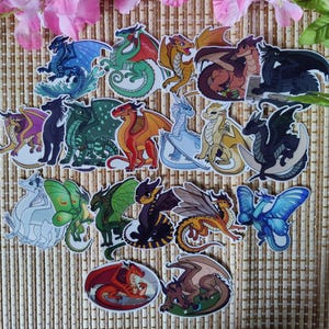 K&ouml;nnte beinhalten: Eine Sammlung farbenfroher Drachenaufkleber in verschiedenen Posen und Designs. Die Aufkleber zeigen Drachen in Blau-, Gr&uuml;n-, Rot-, Orange-, Gelb-, Braun- und Schwarzt&ouml;nen. Einige Drachen haben Fl&uuml;gel, andere befinden sich in verschiedenen Umgebungen.