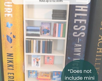 May include: A white miniature bookshelf with multiple shelves, holding tiny books. The shelf is 6.75 inches tall, 2.625 inches wide, and 1 inch deep. The text on the image says it holds up to 102 books. The shelf is labeled "Mini Bookshelf".