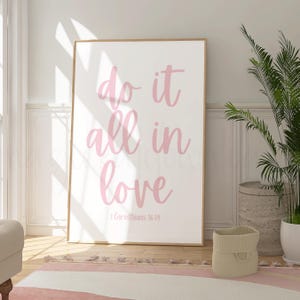 May include: A pink and white framed print with the text "do it all in love" and the scripture reference "1 Corinthians 16:14".