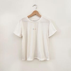 May include: White short-sleeved t-shirt with a small, colorful "ROXY" logo embroidered on the front.