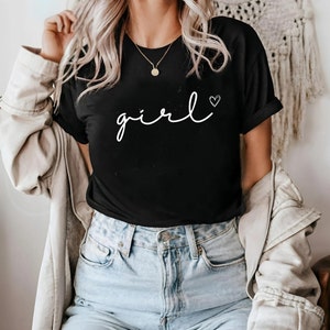 Könnte beinhalten: Schwarzes T-Shirt mit weißem kursivem Text, der "girl" mit einem kleinen Herzsymbol sagt.