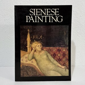 May include: A rectangular book with a black cover featuring the white text SIENESE PAINTING. The cover displays a reproduction of a classical painting showing a figure in a light green gown reclining against a patterned cushion with a gold spire.