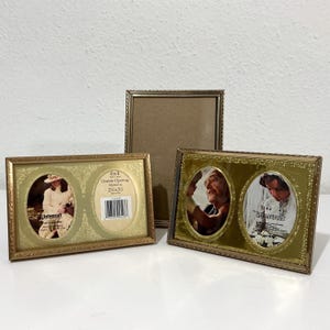 May include: Three metallic picture frames. One is a vertical rectangular frame. Two are horizontal double-opening frames with gold-toned borders and ornate patterns. One frame displays text: 6x4 Double Opening Matted to 2.5x3.5 inches.