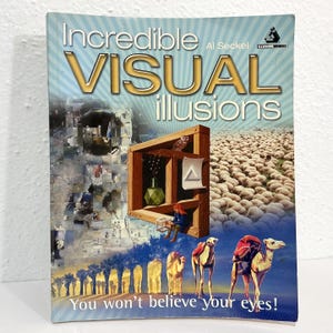 May include: A softcover book titled Incredible Visual Illusions by Al Seckel. The cover features a collage of optical illusions, including a wooden structure, a field of sheep, and camels in a desert, with the text You won't believe your eyes!