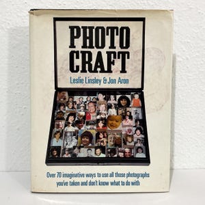 May include: A hardcover book titled Photo Craft by Leslie Linsley and Jon Aron. The cover features a black frame containing a collage of numerous small black and white and color photographs of various people, with the subtitle text below the frame.
