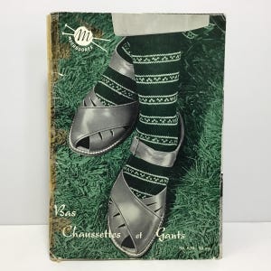 May include: Vintage book cover featuring a pair of gray sandals and green socks with a white geometric pattern. The book's title is "Bas, Chaussettes et Gants". The background is a grassy field.