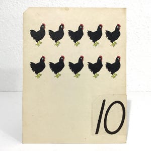May include: Vintage educational card featuring ten black chickens with red combs and green feet. The number "10" is displayed in black on a separate attached piece of paper. The background is a cream color.