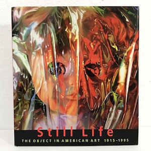 May include: A book cover with a painting of a face obscured by a translucent, crinkled material. The artwork features shades of red, orange, and green. The title "Still Life" is displayed in red, with the subtitle "The Object in American Art 1915-1995" below.