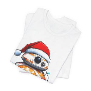 Peut inclure: T-shirt blanc avec un motif festif d'un dro&iuml;de portant un chapeau de P&egrave;re No&euml;l. Le dro&iuml;de est blanc, orange et noir avec un chapeau de P&egrave;re No&euml;l rouge et blanc.