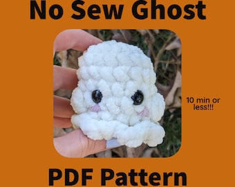 May include: A white crocheted ghost with black eyes and pink cheeks. The ghost is being held in a hand. The text "No Sew Ghost" and "PDF Pattern" are at the top and bottom of the image. The text "10 min or less!!" is in the bottom right corner of the image.