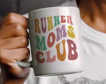 May include: A white ceramic mug featuring the text RUNNER MOMS CLUB printed in a wavy, multi-colored font. The letters are colored in shades of muted pink, teal, yellow, and orange, arranged in three stacked lines on the front of the mug.
