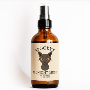 May include: A brown glass room spray bottle with a black spray nozzle. The label reads "Spooky's Midnight Musk" with a black cat graphic. The bottle contains 4 fl oz (118 mL) of room spray.