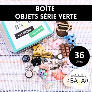 Op de afbeelding: Een groene en witte blikken doos met het opschrift "Ma Boîte à Bazar" en de tekst "Boîte Objets Série Verte" en "Les objets Série Verte" op de deksel. De doos bevat 36 miniatuurvoorwerpen, waaronder een speelgoed saxofoon, een speelgoedtelefoon, een speelgoedtand, een speelgoedgieter en een speelgoed euro-munt.