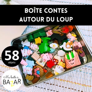 Peut inclure: Une boîte en métal argentée remplie de 58 objets colorés, dont des figurines en bois, des jouets en plastique et de petites babioles. La boîte porte une étiquette noire sur laquelle est inscrit "BOÎTE CONTES AUTOUR DU LOUP" et une étiquette blanche sur laquelle est inscrit "Ma boîte à BAZAR".