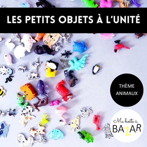 May include: A collection of colourful plastic animal figurines, including a penguin, a turtle, a cat, a dinosaur, a flamingo, a deer, a spider, a bee, a ladybug, a fish, a whale, a squirrel, a giraffe, a frog, a snake, a cardinal, a rooster, a bear, a dolphin, a starfish, and a variety of other animals. The figurines are arranged on a light grey surface. The text "LES PETITS OBJETS À L'UNITÉ" is at the top of the image. The text "THÈME ANIMAUX" is in a black circle in the bottom right corner of the image. The text "Ma boîte à BAZAR" is in a white circle with a black border in the bottom right corner of the image.
