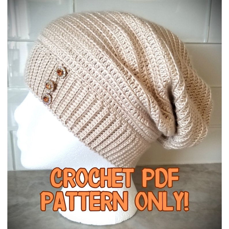 Puede incluir: Un gorro de punto beige con un ajuste holgado y tres botones decorativos. El gorro est&aacute; en una cabeza de maniqu&iacute; blanca. El texto "CROCHET PDF PATTERN ONLY!" est&aacute; en letras naranjas sobre un fondo blanco.