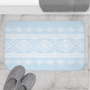 May include: A light blue bath mat with a white geometric pattern. The rectangular mat features repeating diamond and triangle shapes. A pair of gray slippers are at the bottom of the mat.