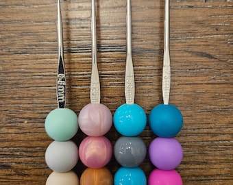 Puede incluir: Cuatro ganchillos de plata de diferentes tamaños: 1,50 mm, 1,25 mm, 1,50 mm y 1,75 mm. Cada gancho tiene una cuenta de colores en el extremo.