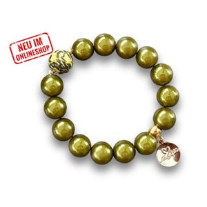 Könnte beinhalten: Ein grünes Perlenarmband mit einem goldenen Anhänger. Der Anhänger trägt die Worte "Amour".