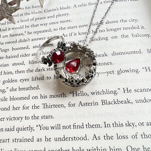 An open book with a ring, necklace, and crown of stars on it. The book is Kingdom of Ash from the Throne of Glass series and the items represent Manon Blackbeak and Dorian Havilliard, hence Hello Princeling