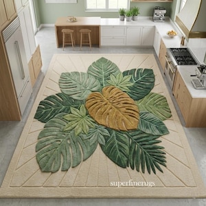 May include: A rectangular area rug featuring a central cluster of tufted monstera and palm leaves in shades of dark green, light green, and mustard yellow, set against a cream background with geometric line accents and the text superfinerugs.