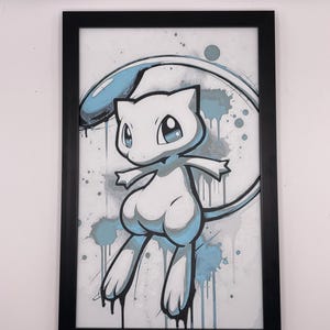 May include: Framed artwork featuring a stylized illustration of Mew, a Pokémon character. The artwork uses a white, blue, and gray color palette with a splatter effect. The black frame surrounds the image, which is mounted on a white background.