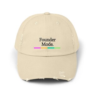 以下が含まれることがあります： 「Founder Mode.」という黒い文字と、その下にカラフルなストライプが施された、ベージュのダメージ加工が施されたベースボールキャップです。