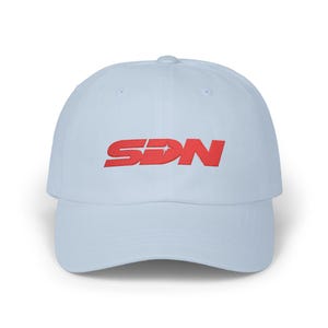 Peut inclure: Casquette de baseball bleu clair avec les lettres rouges "SDN" brodées sur le devant. La casquette a une visière incurvée et une conception à six panneaux. Le texte comprend un motif d'étoile.
